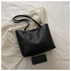 Dettaglio di una borsa tote in pelle nera opaca con testo FASHION & BAGS su tessuto bianco