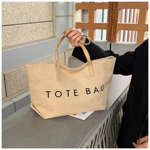 Détail du cabas en toile beige avec inscription TOTE BAG noire et poignées solides