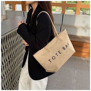 Détail d'un grand sac cabas beige minimaliste porté par un mannequin en blazer