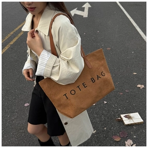 Gros plan sur un sac cabas marron en daim avec bandoulière en cuir au style urbain
