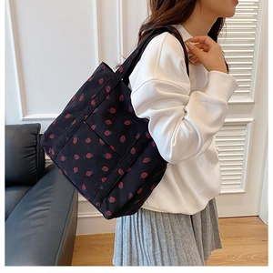 Detailed view of large capacity black corduroy tote bag with red strawberry pattern print