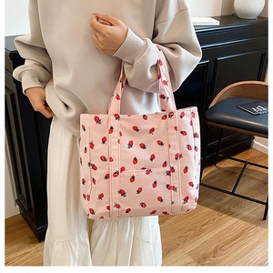Detail of pink corduroy tote bag with strawberry prints and a practical front pocket