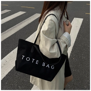 Gros plan détaillé d'un grand sac cabas noir minimaliste avec impression texte TOTE BAG blanc
