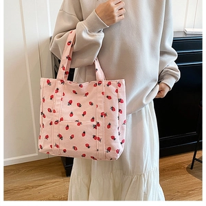 Détail du cabas en velours côtelé rose avec imprimé fraises et poche avant pratique