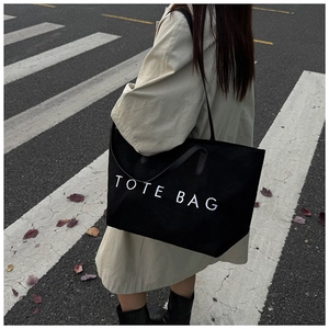 Photo en extérieur d'un grand sac cabas noir en toile avec broderie TOTE BAG et anses