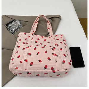Nahaufnahme der rosa Cord-Tasche mit Erdbeerdruck und praktischer Fronttasche