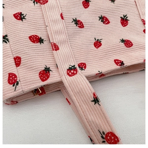 Detail einer rosa Cord-Schultertasche mit Erdbeerdruck und Metallschnallen-Verschluss