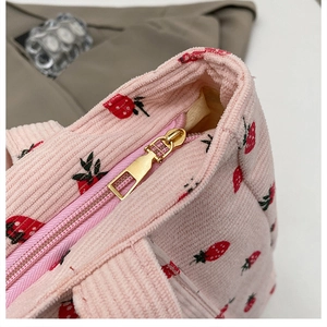 Nahaufnahme einer rosa Cord-Tragetasche mit Erdbeermuster und goldenem Reißverschluss