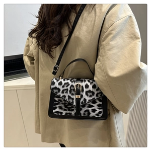 Detail of black and white leopard print shoulder bag with gold clasp on model