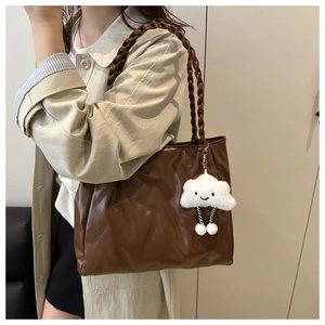 Detail of dark brown pleated tote bag with woven handles and cute cloud charm