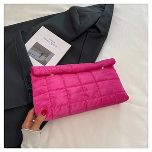 Detailed close-up of rose red quilted envelope clutch with gold fasteners and down texture