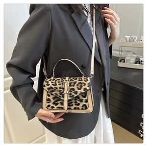 Detailed view of leopard print crossbody bag with gold buckle on a gray blazer model