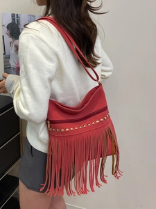 Large red leather tassel tote bag with gold studs and adjustable shoulder strap for women