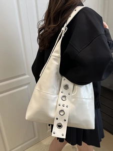 Fashionable cream white leather hobo bag with large silver metal eyelets on wide strap