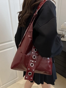 Deep red patent leather shoulder bag with oversized metal eyelet strap details