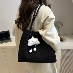 Detail of black jacquard tote bag with textured pattern and cute cloud charm accessory