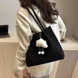 Detail of black tote bag featuring waffle texture and cute cloud charm on shoulder