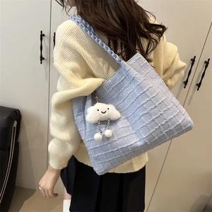 Detailed texture of light blue woven shoulder bag with cute cloud plush charm detail