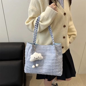 Close-up of light blue tweed tote bag with woven texture and plush cloud charm