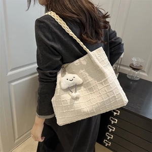 Detail of cream woven tote bag featuring braided straps and cute cloud plush pendant