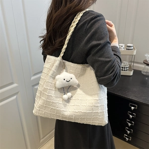Detail of white tweed tote bag featuring woven texture and a cute plush cloud charm