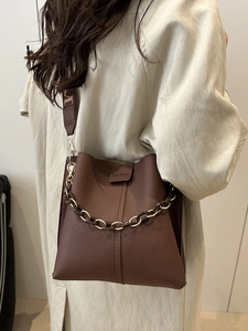 Dark brown lychee texture bucket bag with chain strap and wide textile shoulder strap