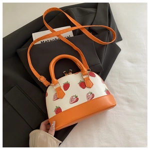 Detail of strawberry print on contrast shell bag with stitching and gold zipper
