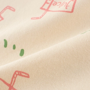 Close-up of soft cotton fabric with cute pink juice box and green polka dot prints