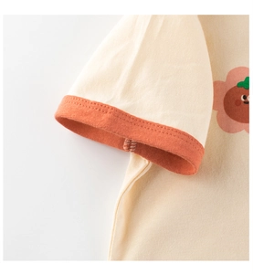 Detalle de manga de punto con puño acanalado naranja y estampado floral en camiseta beige