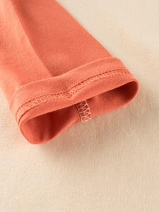 Détail des coutures de haute qualité sur le T-shirt orange à manches longues pour enfant