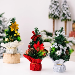 Detailed view of mini Christmas trees with red flowers, pine cones and rustic fabric bases