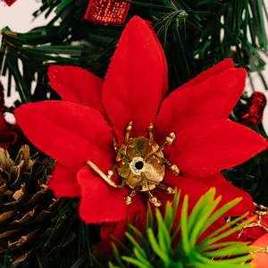 Close-up of artificial poinsettia with green pine needles and natural brown pine cone