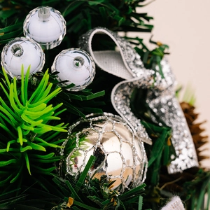 Detail of a mini Christmas tree with silver mesh ball and green pine needle accents