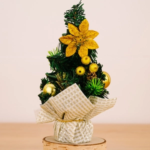 Close-up of a mini Christmas tree with gold flowers, berries and a wooden base