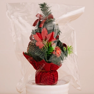Macro detail of mini Christmas tree featuring red poinsettia, pine cones and red bows