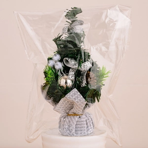 Detailed view of mini Christmas tree with silver bows and cones in clear packaging