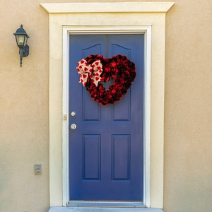 Close-up of heart-shaped buffalo plaid wreath with burlap bow hanging on a blue door