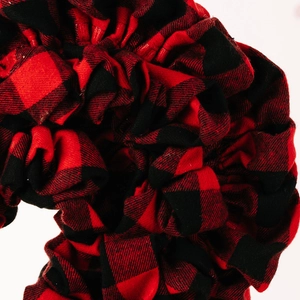 Detailed macro shot of a red and black buffalo plaid fabric heart ornament with ruffled texture