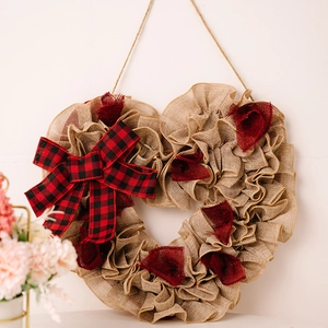 Detailed view of rustic burlap heart wreath with buffalo plaid bow and red fabric accents