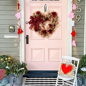 Close-up of heart-shaped burlap wreath with red fabric roses on a pink front door