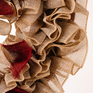 Macro shot of rustic red and beige burlap heart wreath showing detailed natural fiber texture