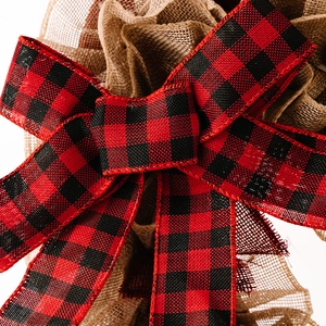 Detailed close-up of red and black buffalo plaid ribbon bow with rustic burlap texture