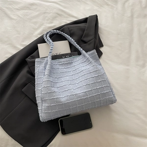 Detail of light blue tote bag featuring textured seersucker fabric and woven handles