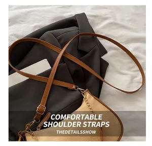 Detail showing beige litchi leather texture and brown strap with gold zipper accents
