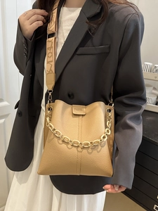 Elegant khaki lychee leather bucket bag with wide fabric strap and gold chain detail