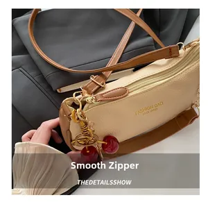 Detail of beige lychee grain leather bag with golden zipper and cherry charm accessory
