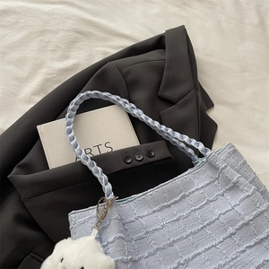 Detail of light blue checkered handbag showing woven handle and plush cloud charm accessory