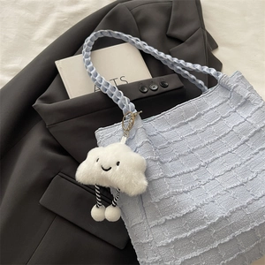 Detail of light blue quilted tote bag texture with cute plush cloud charm accessory