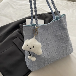 Close-up of light blue quilted tote bag with woven handles and fluffy cloud charm