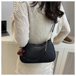Detail of black lychee leather crescent hobo bag with gold chain and cherry charm